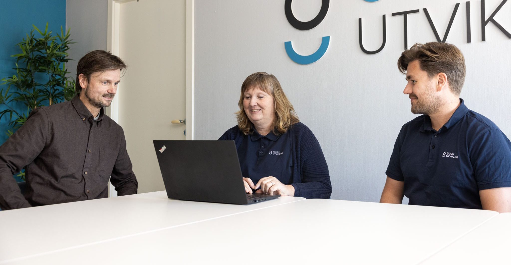 bildet viser tre ansatte hos guru utvikling i et møte